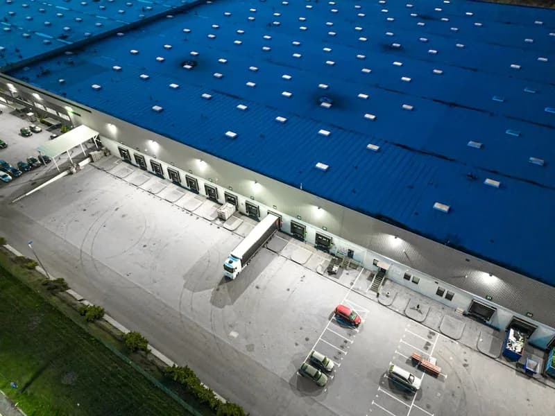 Centro logístico de noche con andenes de carga y equipos de climatización sobre la cubierta